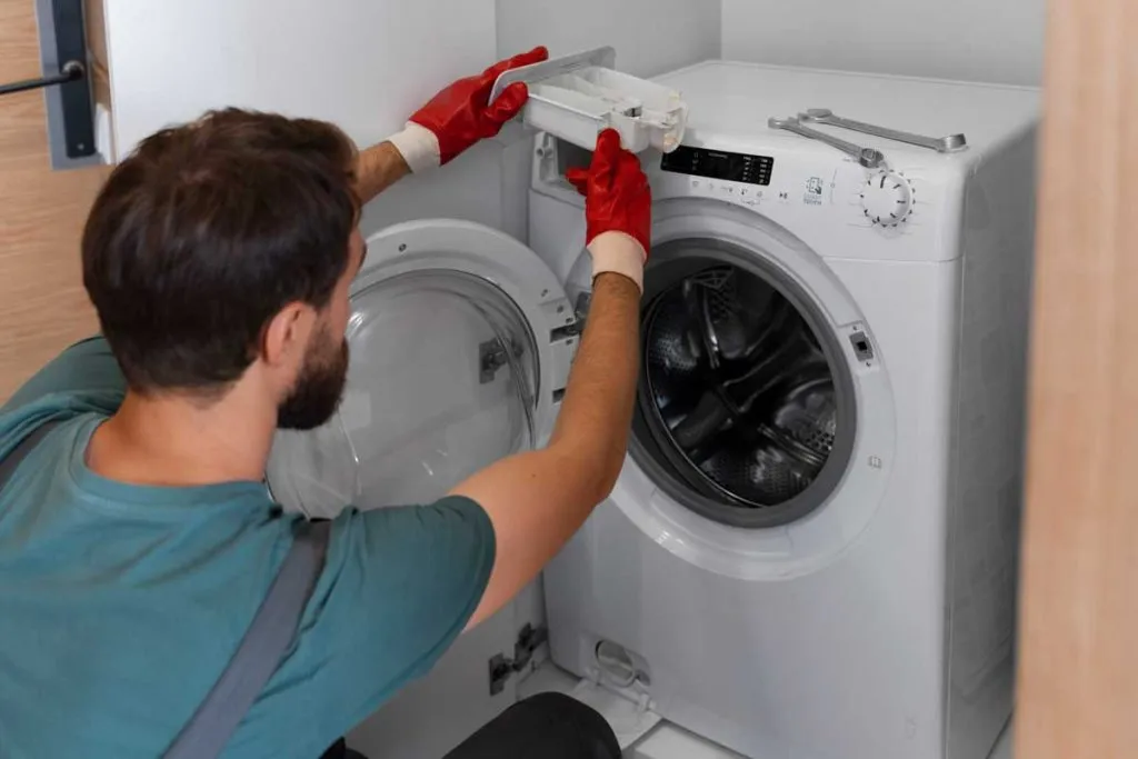 repairman in red gloves in repairing washer in Kitchener